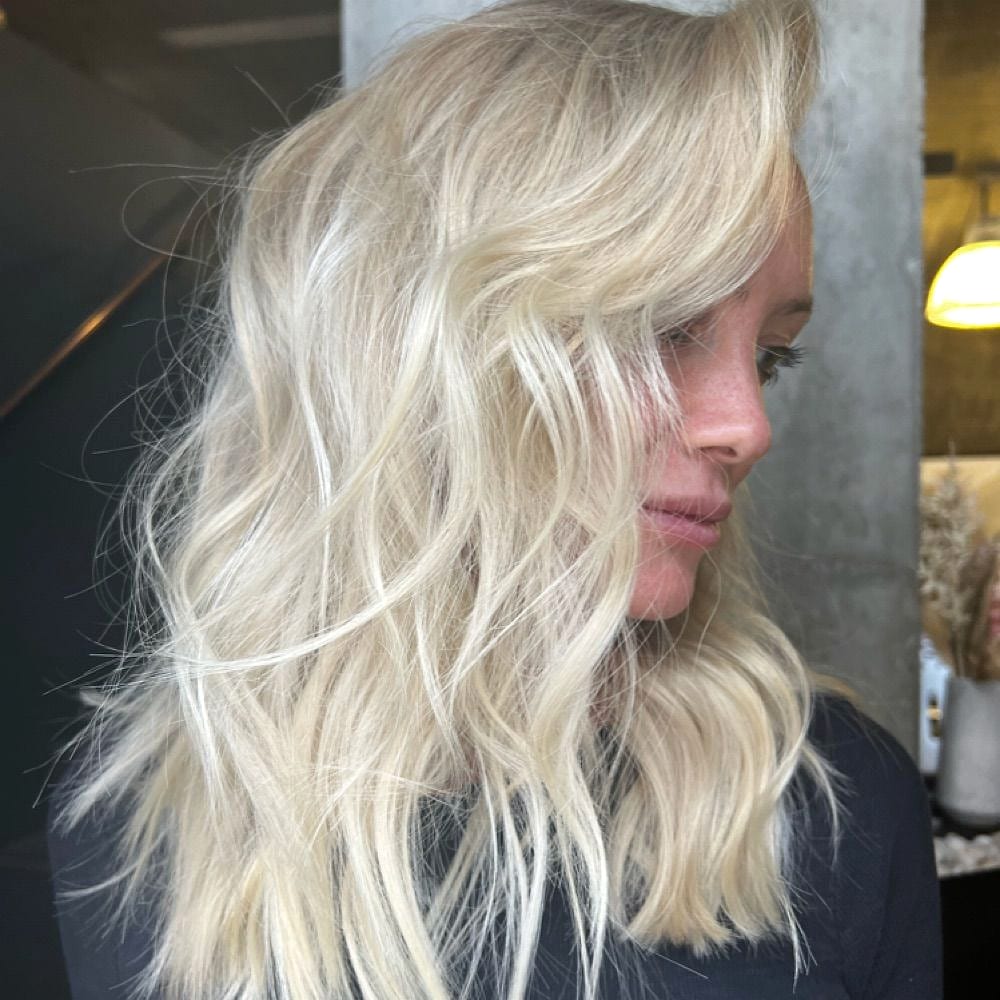 Side profile of a woman with wavy platinum blonde hair in a salon